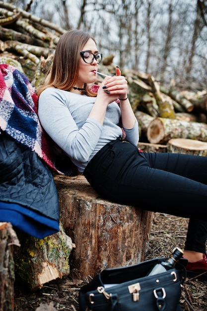 Sigaretta di fumo della ragazza nella foresta