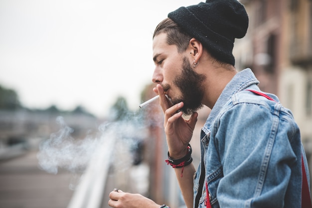 sigaretta fumatori di giovane uomo bello hipster con la barba