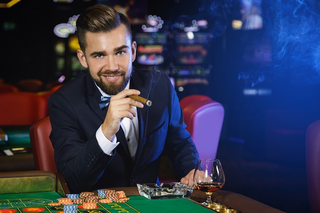 Sigaro di fumo dell'uomo bello ricco nel casinò