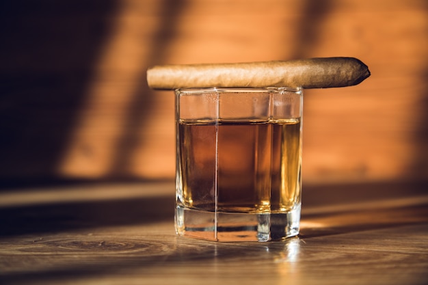 Sigaro su un bicchiere di whisky sul tavolo