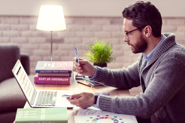 Significato speciale. Simpatico uomo barbuto che guarda la carta dei tarocchi mentre la tiene davanti a sé