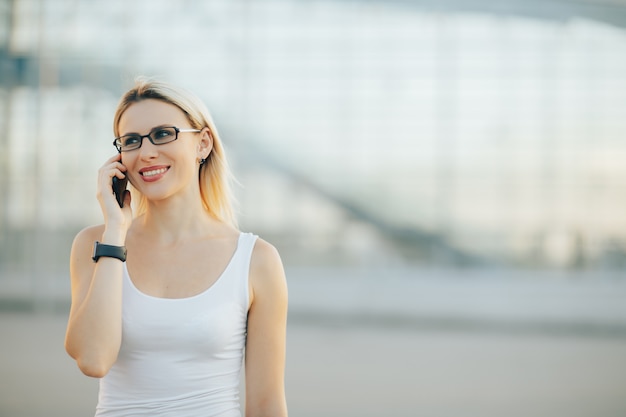 Signora alla moda con gli occhiali parlando al telefono e sorridente