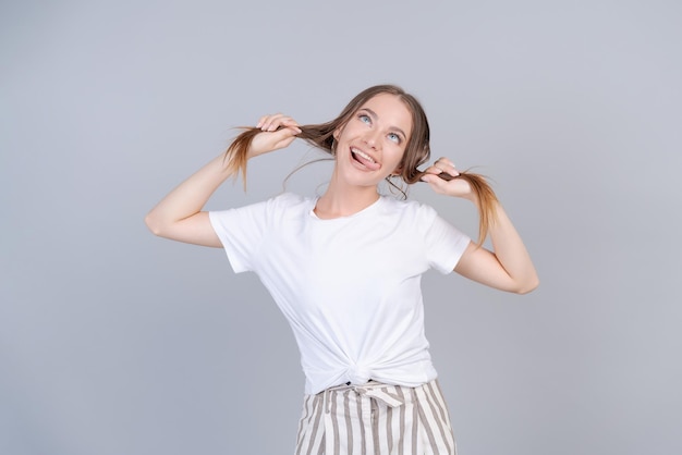 Signora allegra in pantaloni a righe che scherza in studio e si tiene i capelli