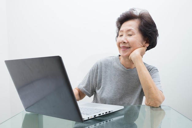 Signora anziana che lavora con il computer portatile, funzionante con il computer portatile