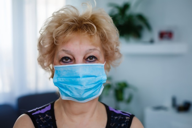 Signora anziana che tiene una maschera facciale per la protezione contro il virus dell'influenza.