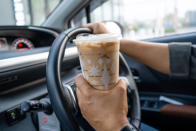 Signora asiatica che tiene caffè freddo per bere cibo in auto