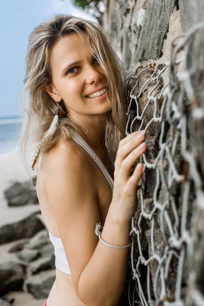 Signora bionda attraente sexy che posa sulla spiaggia che prende il sole Foto verticale