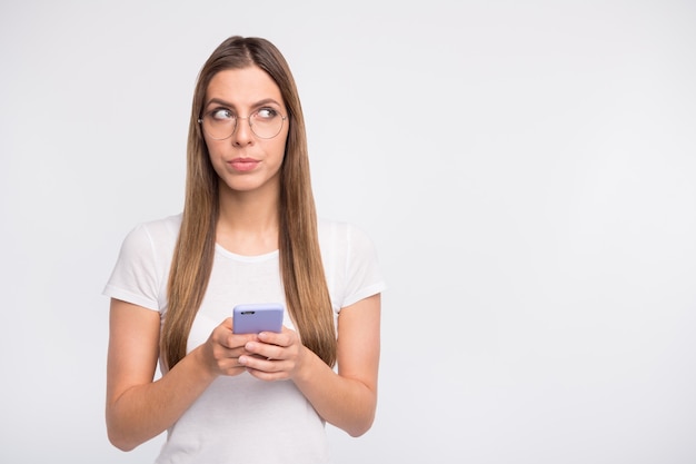 signora bruna con gli occhiali in posa contro il muro bianco con il suo telefono