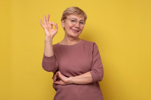 Signora caucasica senior sorridente che gesturing segno perfetto