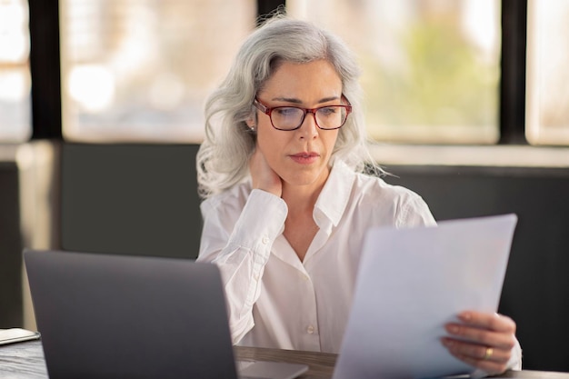 Signora che legge bollette e rapporti che lavorano con documenti in ufficio