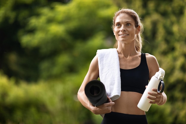 Signora esile felice che fa yoga al parco pubblico