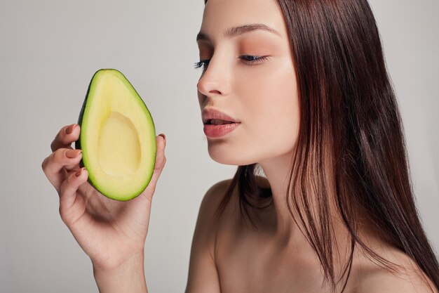 Signora nuda tenera attraente che esamina avocado