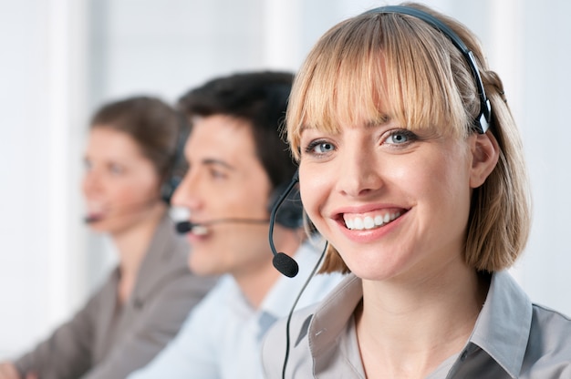 Signora sorridente che lavora all'ufficio del call center con i colleghi