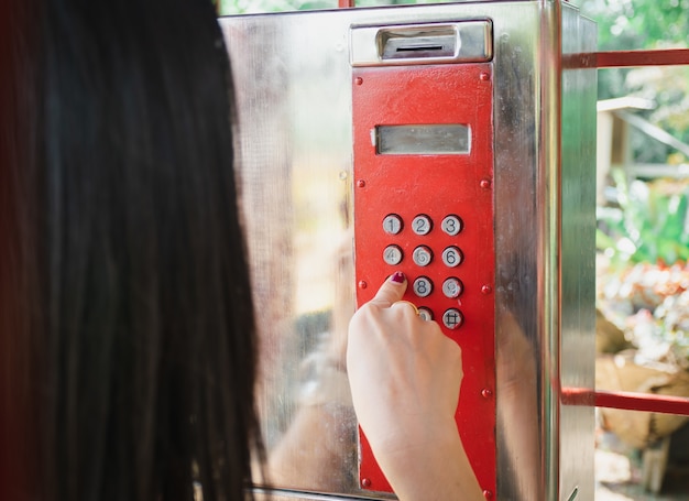 Signora telefono nella vecchia annata rossa della cabina telefonica pubblica