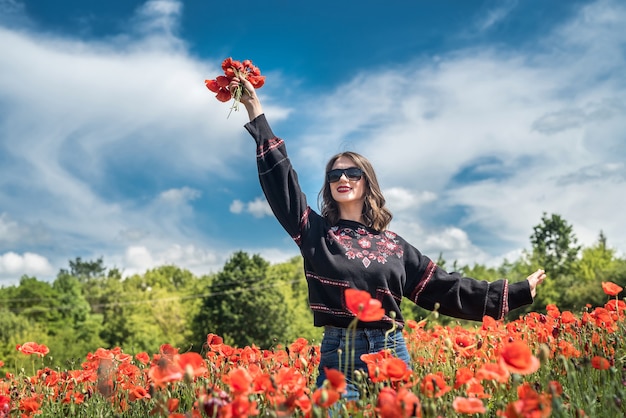 Signora ucraina che cammina lungo un campo di papaveri