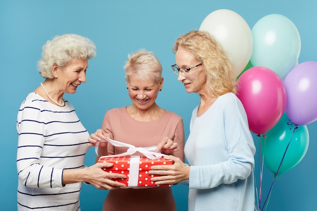 Signore senior che aprono insieme il contenitore di regalo