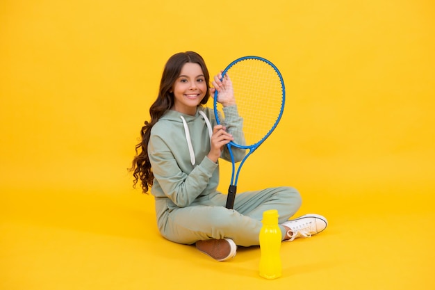 Sii idratato bambino seduto con racchetta e bottiglia d'acqua bambino con racchetta da tennis