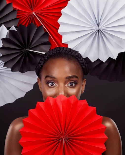 Sii il tuo più grande fan Foto in studio di una bella giovane donna in posa con un fan di origami su uno sfondo nero