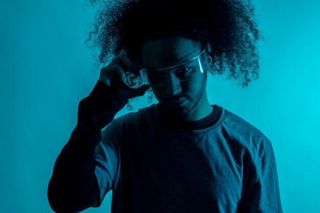 Silhouette con luce blu con occhiali led futuristici Giovane con capelli afro su sfondo bianco