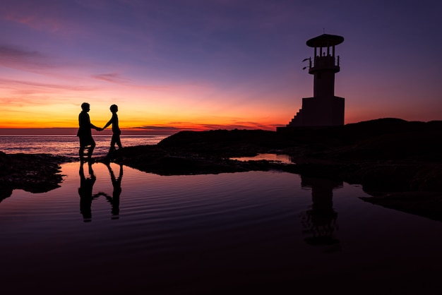 Silhouette Coppia romantica con faro al momento del tramonto