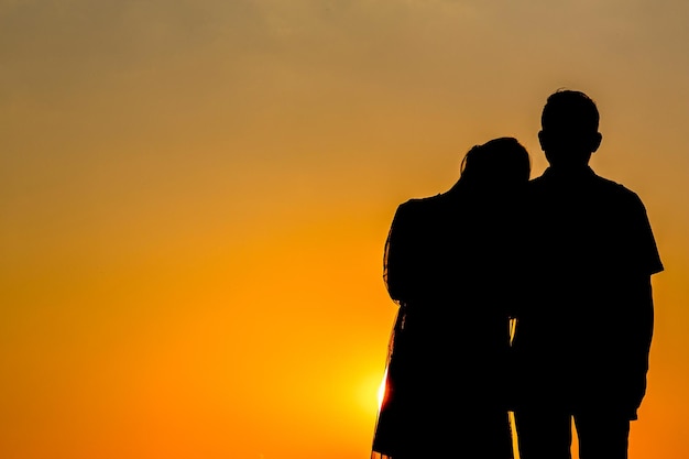 Silhouette di amanti che si tengono per mano abbracciati insieme al tramonto amore innamorato