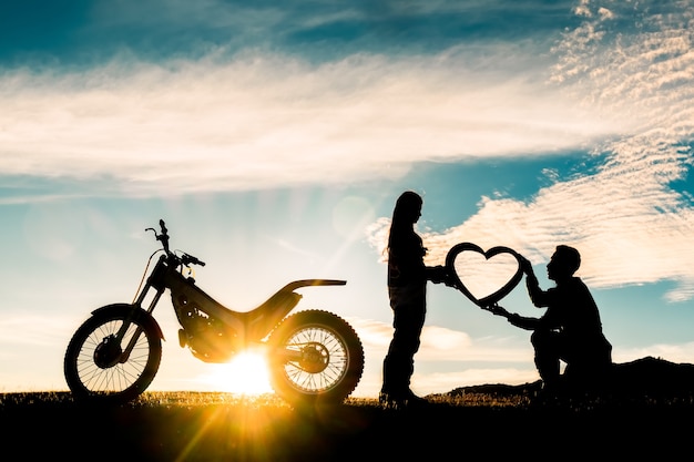 silhouette di amanti romantici e motocross con tramonto