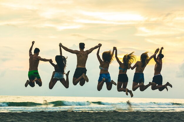 Silhouette di amici che saltano sulla spiaggia