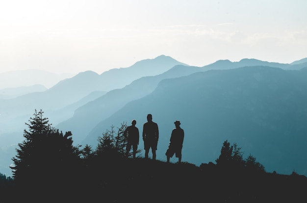 Silhouette di amici in piedi vicino alle montagne contro il cielo in tempo nebbioso