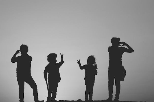 Silhouette di bambini che fanno gesti contro un cielo limpido
