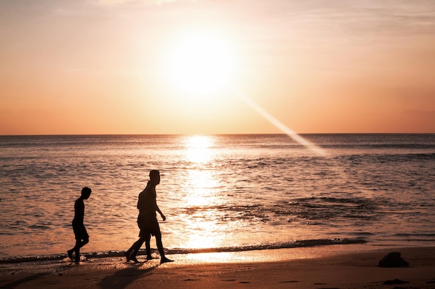 Silhouette di bambini su Bella vista del cielo al tramonto sulla spiaggia