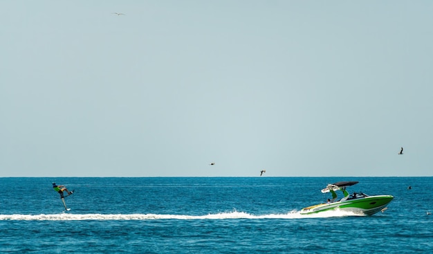 Silhouette di barca a motore e wakeboarder che saltano trucco pazzo wakeboarder facendo trucchi sul mare