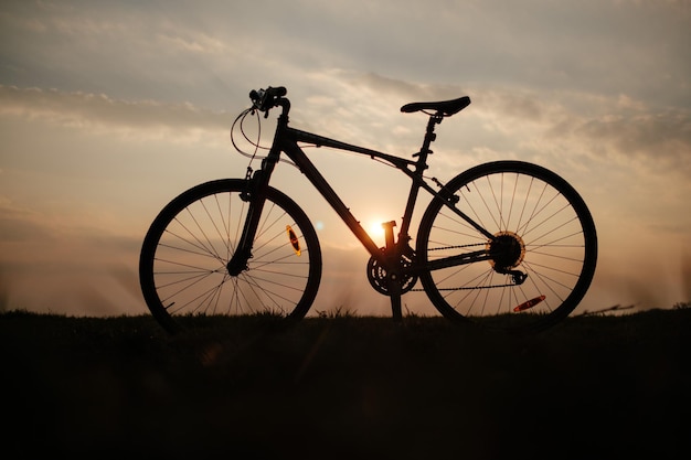 Silhouette di bicicletta sul campo contro il cielo durante il tramonto