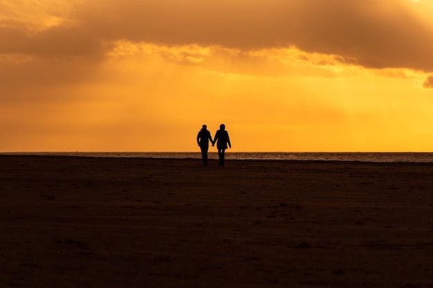 Silhouette di coppia che cammina guardando il tramonto sulla spiaggia