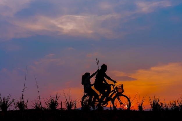 silhouette di coppia che guida bici tempo felice tramonto