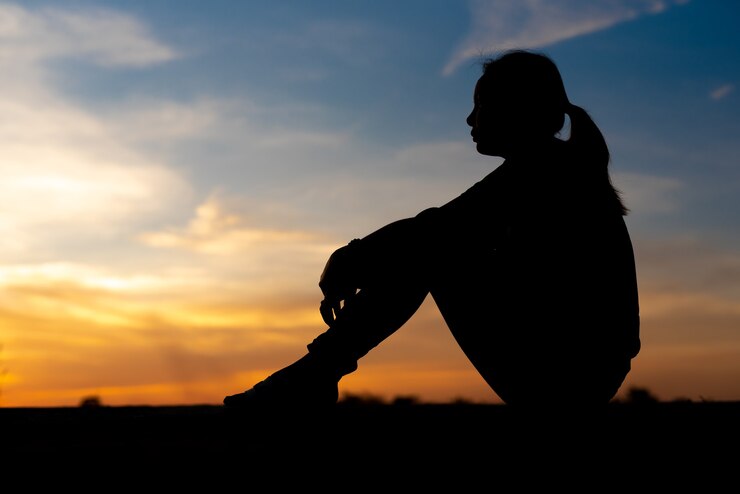 Silhouette di donne tristi e depresse sedute al passaggio pedonale del parco con il tramonto