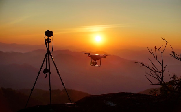 Silhouette di drone e fotocamera con catena montuosa al tramonto