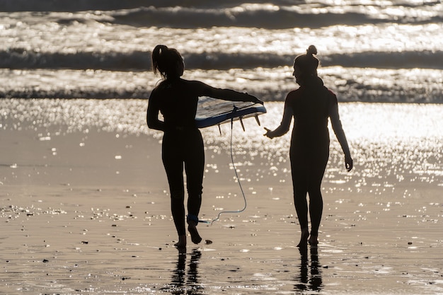 silhouette di due surfisti che camminano sulla spiaggia di La Serena vista posteriore