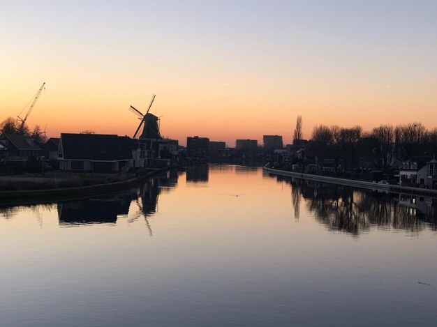 Silhouette di edifici sul fiume contro il cielo durante il tramonto