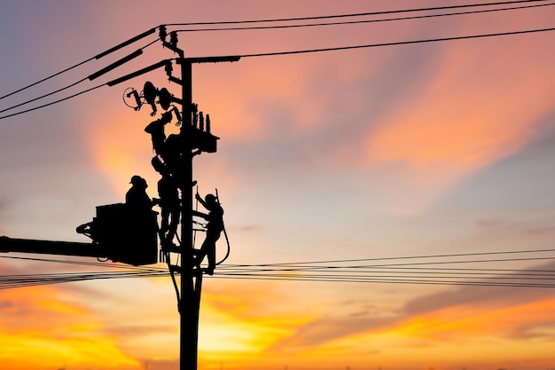 Silhouette di elettricista guardalinee riparatore lavoratore al lavoro di arrampicata su palo di alimentazione elettrica