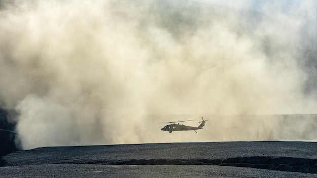 Silhouette di elicottero militare che atterra o decolla in una nuvola di polvere