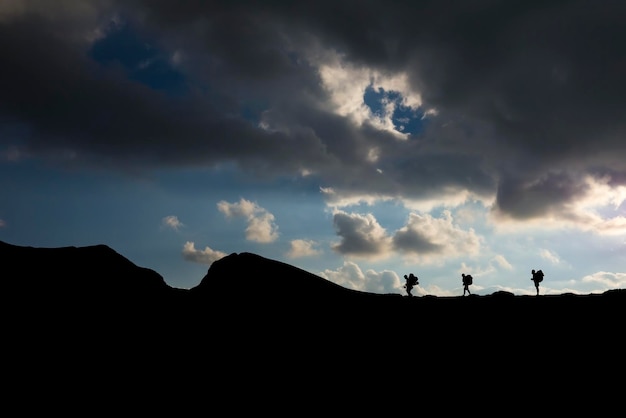 Silhouette di escursionisti con zaini che scalano la montagna