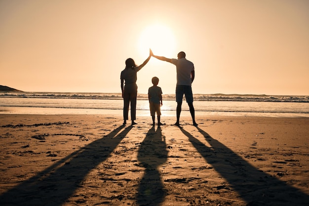 Silhouette di famiglia alla protezione della spiaggia e al tramonto con la sicurezza e la protezione delle persone con genitori e figli all'aperto Madre padre e figlio nella natura indietro e vista sull'oceano con amore cura e sostegno