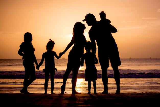 Silhouette di famiglia sulla spiaggia al tramonto.