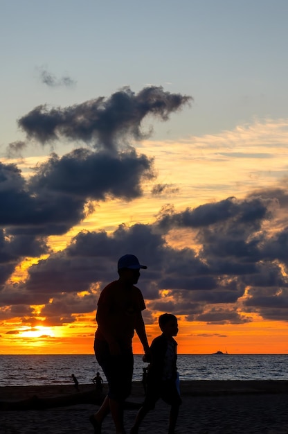 Silhouette di fratellini che giocano sulla spiaggia al tramonto