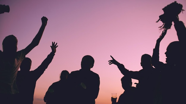 Silhouette di giovani ballerini di gruppo hanno una festa in spiaggia al tramonto