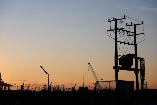 Silhouette di gru sul cantiere contro il cielo durante il tramonto