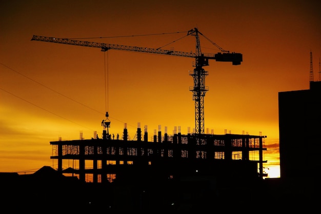 Silhouette di gru sul cantiere durante il tramonto