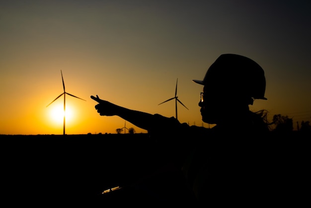 Silhouette di ingegnere femminile che lavora e tiene il rapporto presso l'azienda agricola di turbine eoliche Power Generator Station su mountainThailand persone