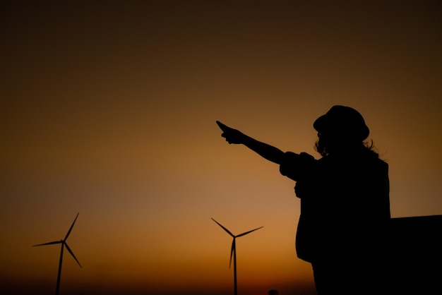 Silhouette di ingegnere femminile che lavora e tiene il rapporto presso l'azienda agricola di turbine eoliche Power Generator Station su mountainThailand persone