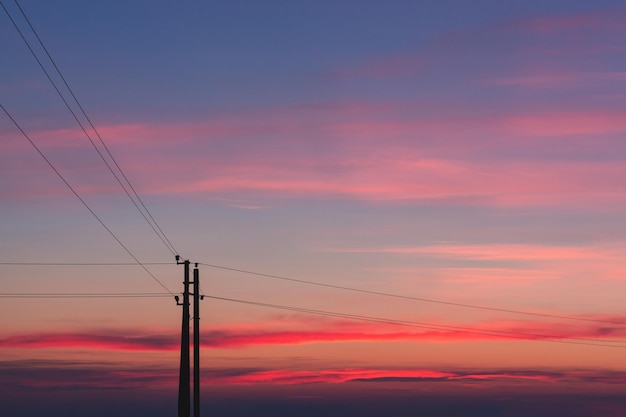 Silhouette di linee elettriche sullo sfondo di un tramonto luminoso, cavi ad alta tensione